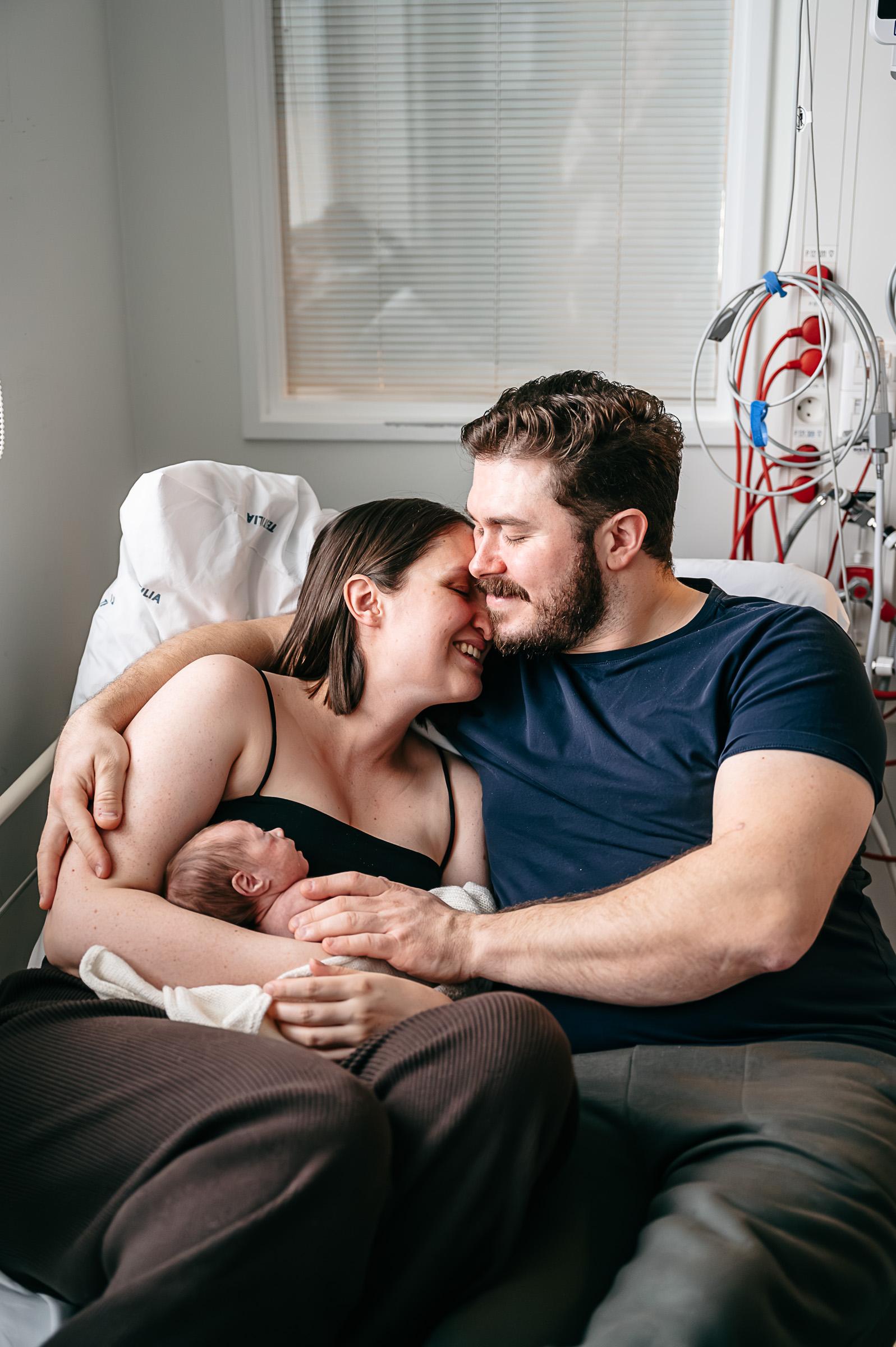 Forældre ligger tæt i hospitalsseng med deres for tidlig fødte barn